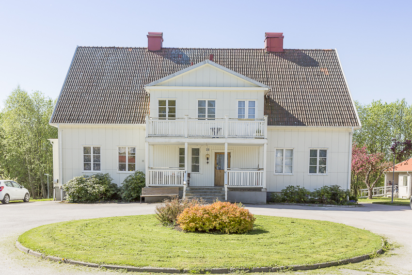 Stor vit villa med rondellformad uppfart framför huset.